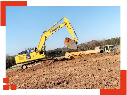 A yellow excavator truck transferring dirt to another truck